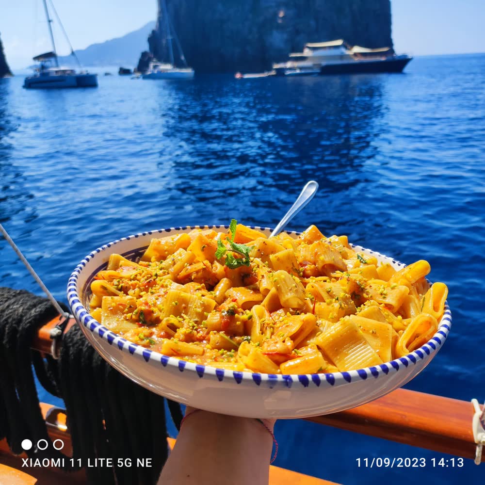 Un piatto di pasta servito a bordo, col mare dietro