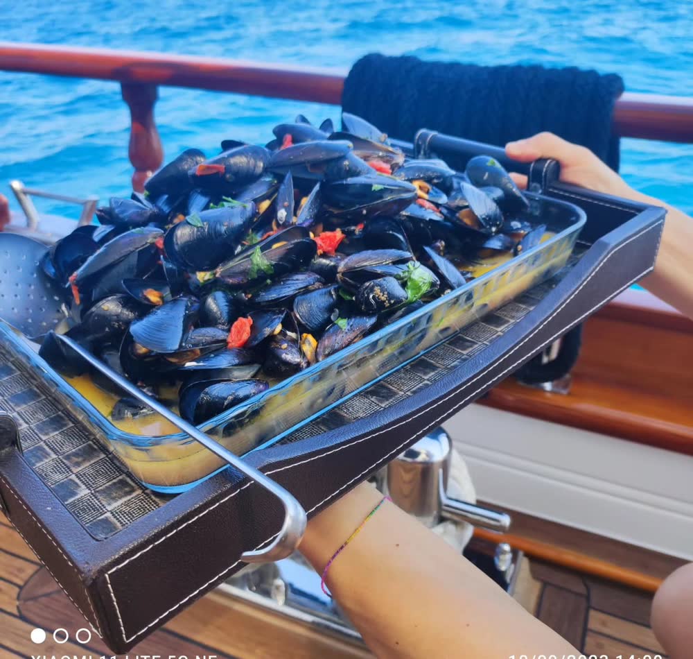 Una teglia di cozze, tenuta sopra il mare